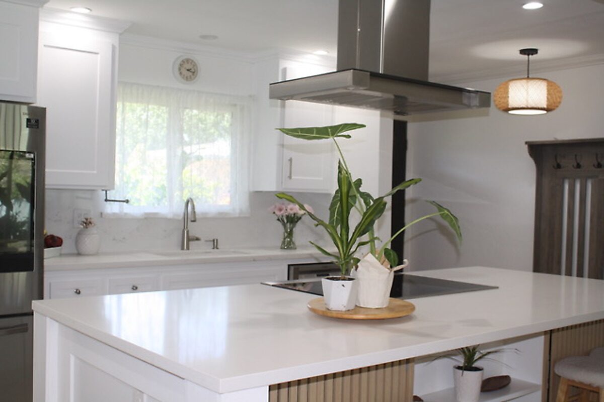 Kitchen after remodel — white shaker cabinets, quartz island, wood slat bar